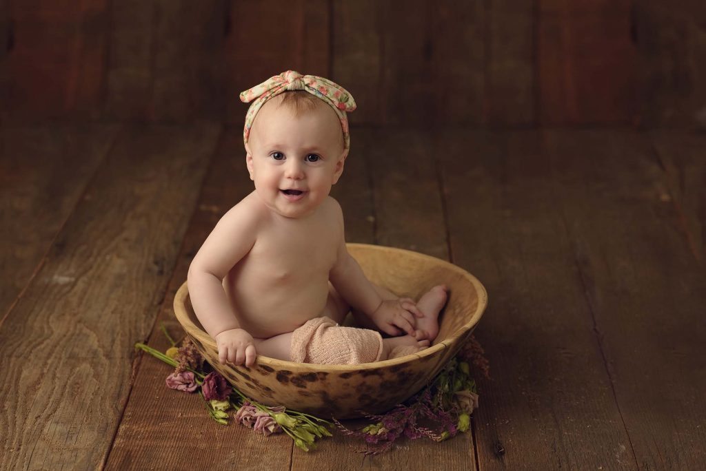Baby Girl In A Wooden Bowl Wearing A Big Bow Headband