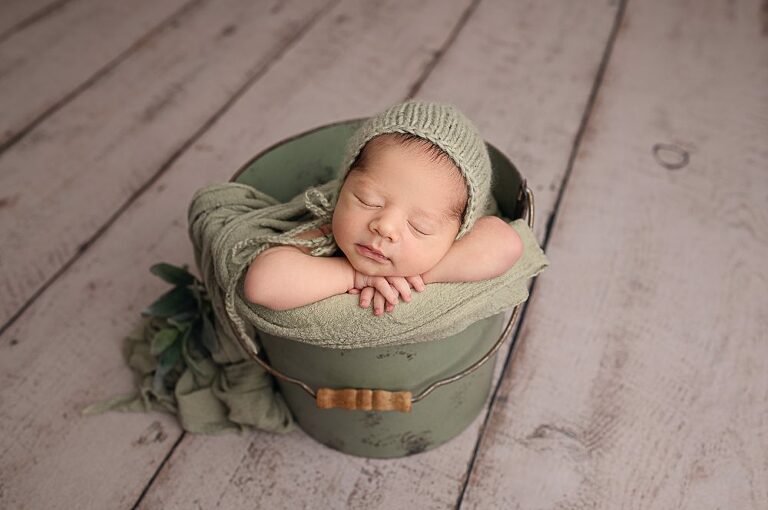 Baby relaxing in a calming green bucket at Newborn Photography Experience